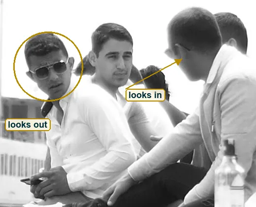 Crop of the young men on the wall, one in aviator sunglasses facing out, the others facing in