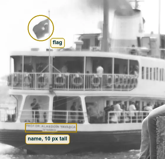 Crop of the ferry stern with its painted name, the flag and the life rings