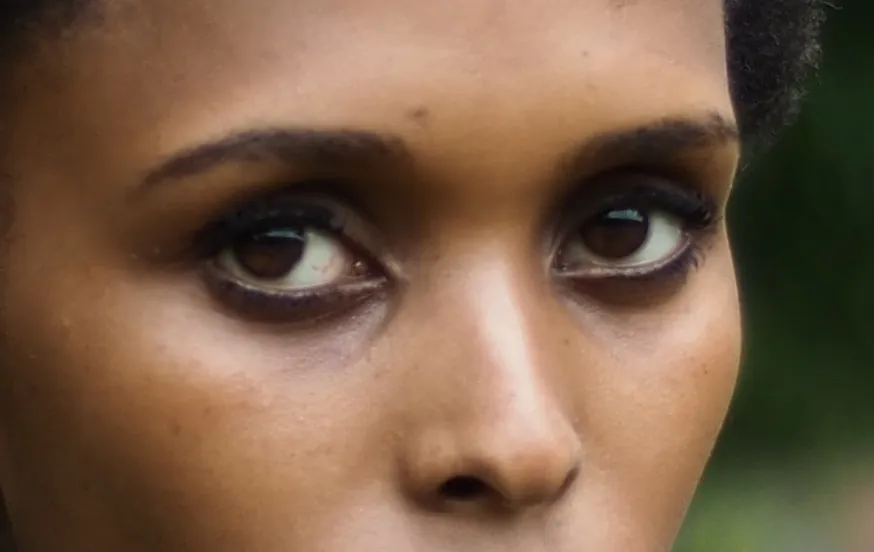 Close crop of her eyes under low straight brows, turned back toward the lens