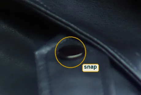 Pixel-level crop of the leather lapel and its snap button, smooth tone with no film grain clumps