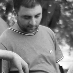 Crop at full size of the young man's face and grey T-shirt, showing fine even texture