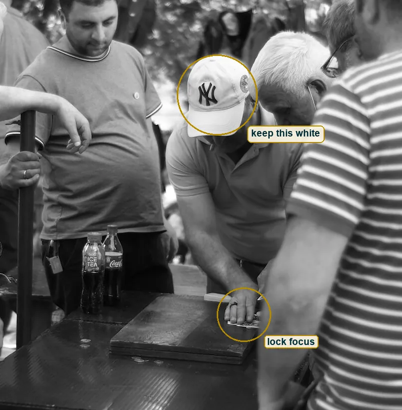 Crop of the centre of the scene with circles on the dealer's hand for focus and on the white cap for exposure