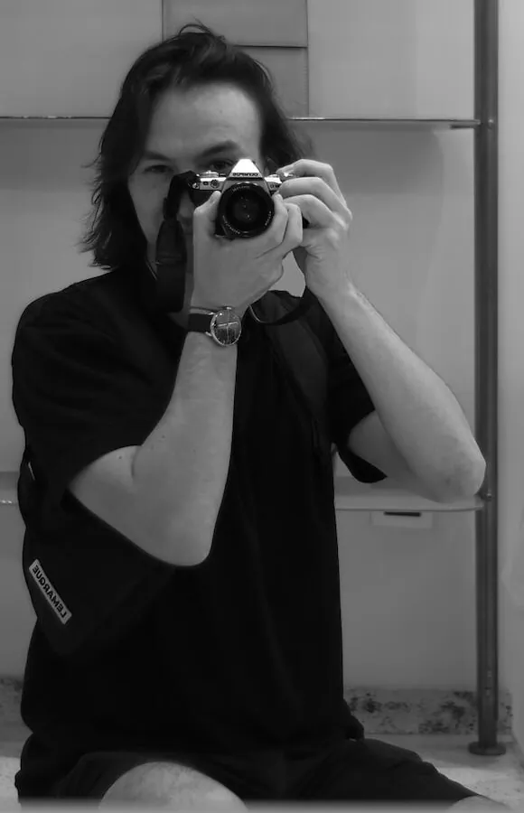 Tight crop of the seated figure behind the camera, no marks