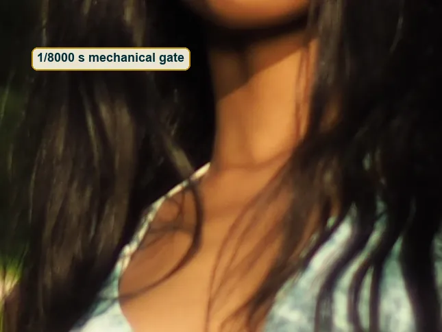 Pixel-level crop of her shoulder and patterned top with razor-sharp hair strands in sunlight