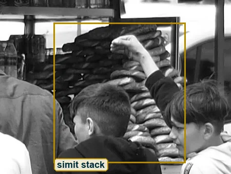 Crop of the simit cart, sesame bread rings stacked in a tall column, with the van behind