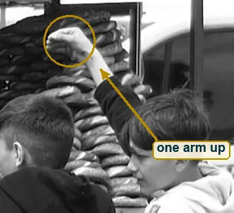 Crop of a raised fist at the top of the simit stack and the dark sleeve leading down to a boy in a two-tone hoodie