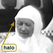 Crop at full resolution of the white headscarf against the dark van window, with a bright rim along the edge