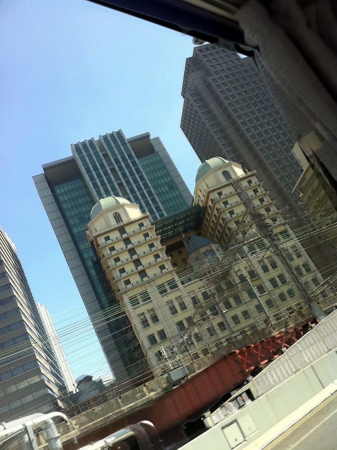 Looking up past railway wires at towers and a building with two green domes